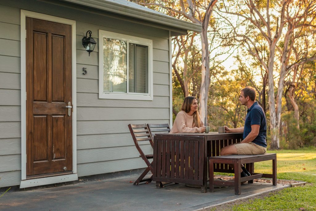 A couple sit outside a cabin at a family reunion accommodation venue in Sydney