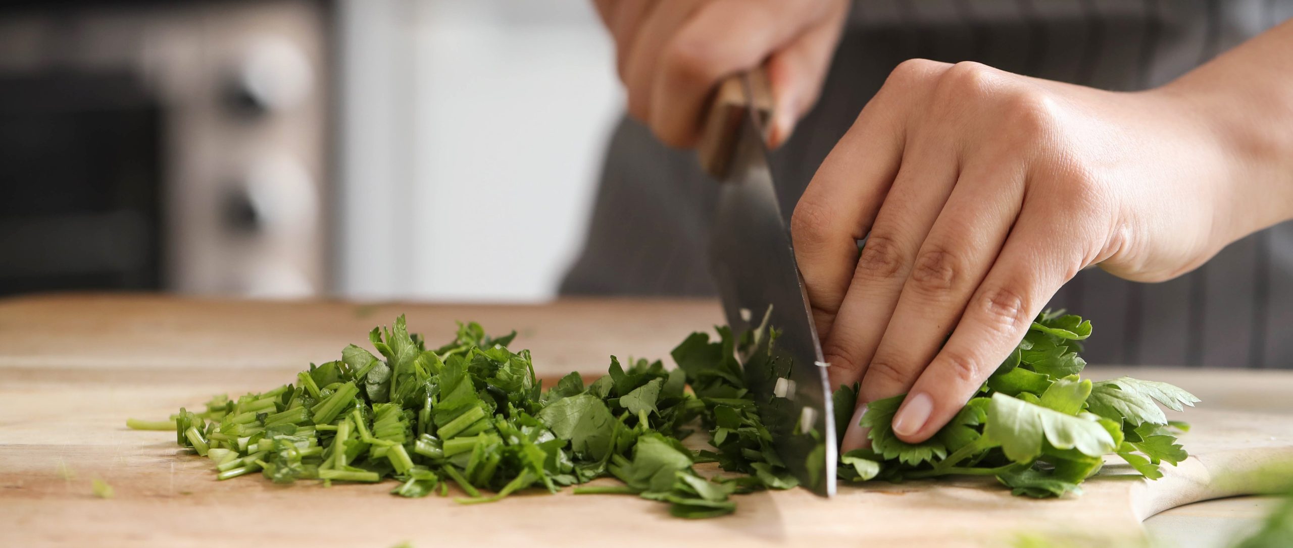 A close-up photo of a woman chopping parsley for meal catering at Long Point Conference Centre.